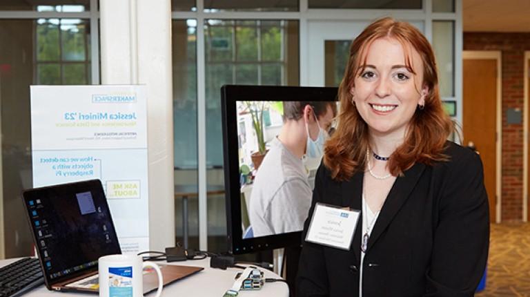 A U N E student poses with her project at the innovation showcase