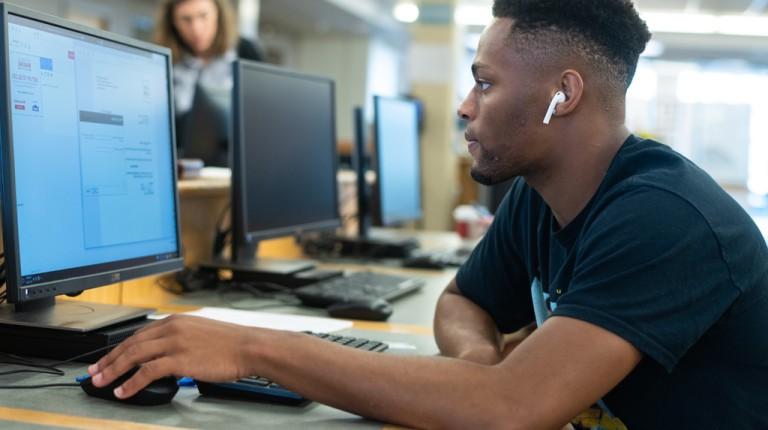 A student uses the computer in the Biddeford Campus library