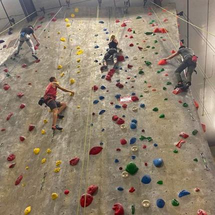 Three students climbing an indoor rock wall