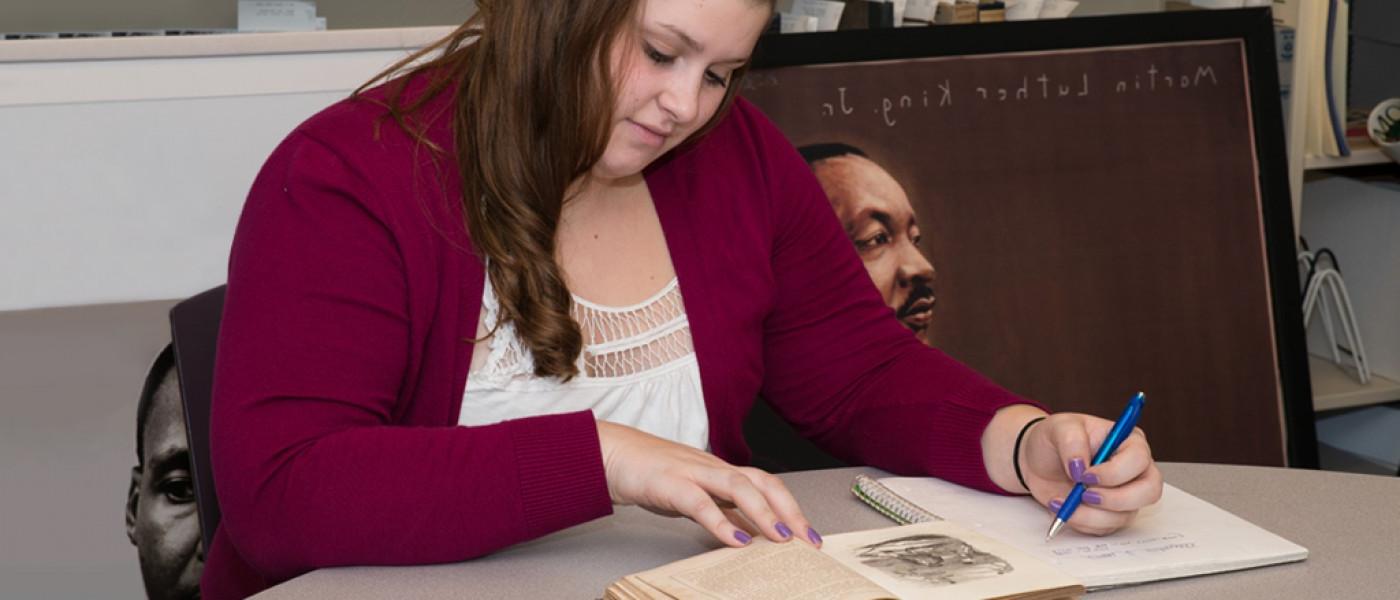 A U N E liberal arts students takes notes while reading