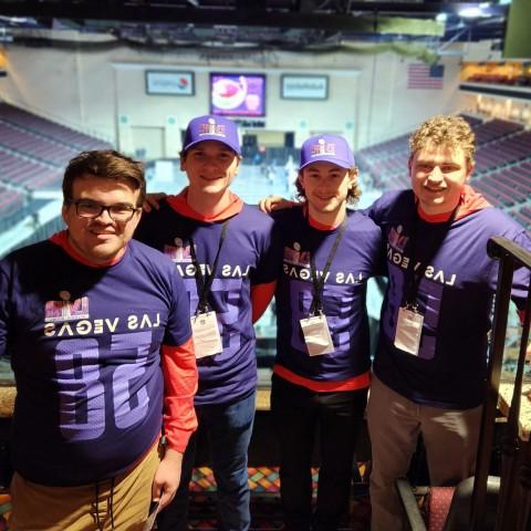 Four students pose wearing NFL-themed shirts